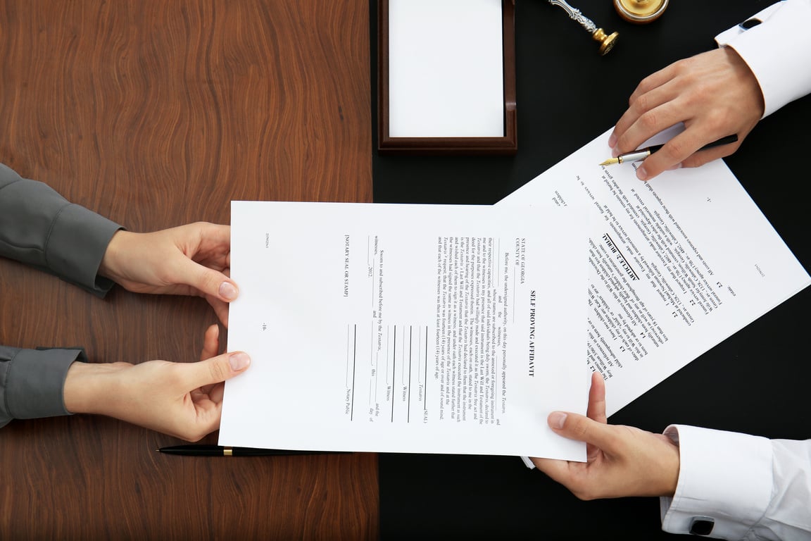 Woman Passing Documents to a Notary Public