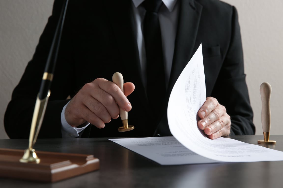 Male Notary Stamping Document at Table, Closeup